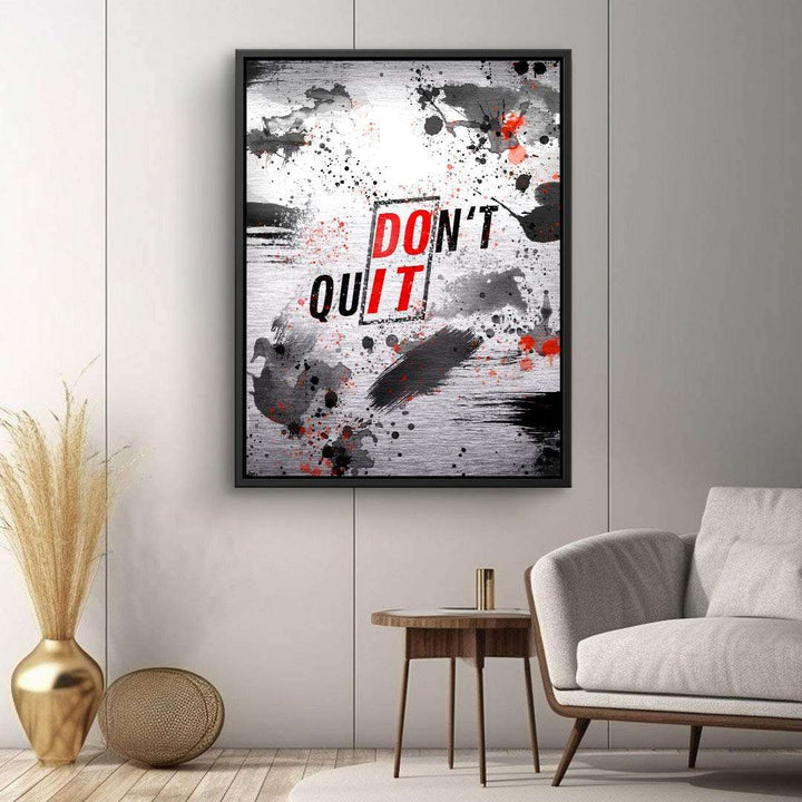 Modernes Wandbild mit abstrakten Schwarz-Rot-Farbspritzern und Motivationsspruch 'Don't Quit' im Wohnzimmer.