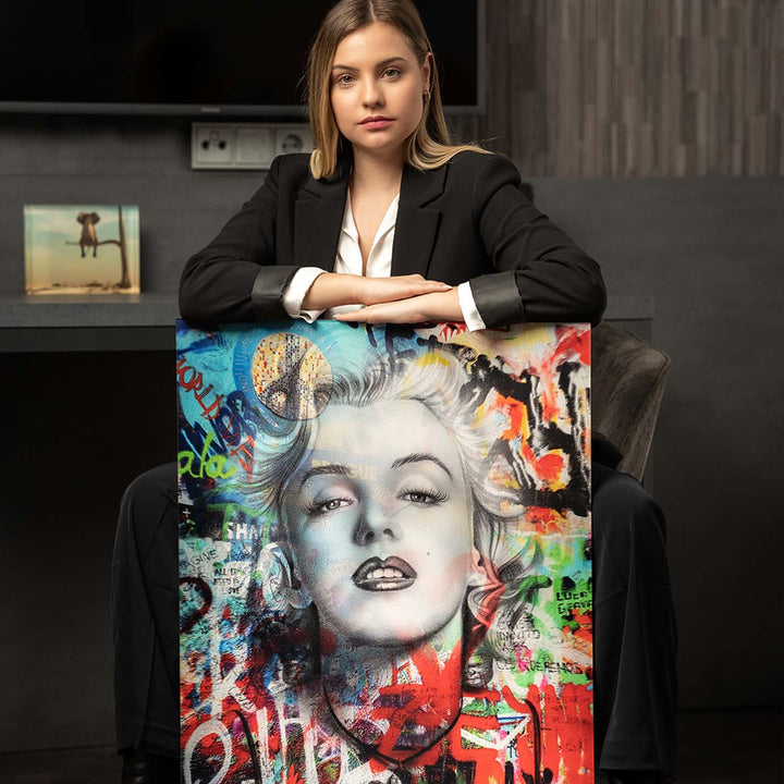 Frau im Anzug präsentiert modernes Pop Art Wandbild mit Marilyn Monroe Motiv, bunte Graffiti-Elemente