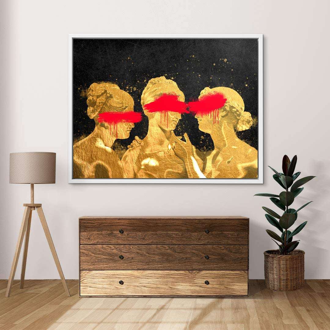 Modernes Wandbild mit goldenen, klassisch inspirierten Figuren auf schwarzem Hintergrund, rote Streifen über den Augen, dekorativ im Wohnzimmer mit Lampe und Pflanze.