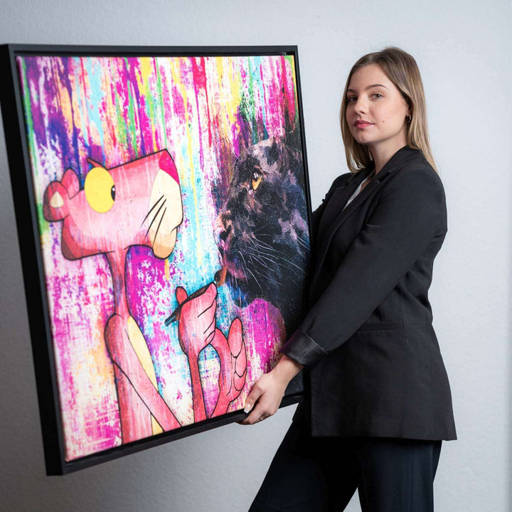 Frau hält Leinwandbild mit Pop Art Motiv, Pink Panther und schwarzer Panther vor buntem Hintergrund