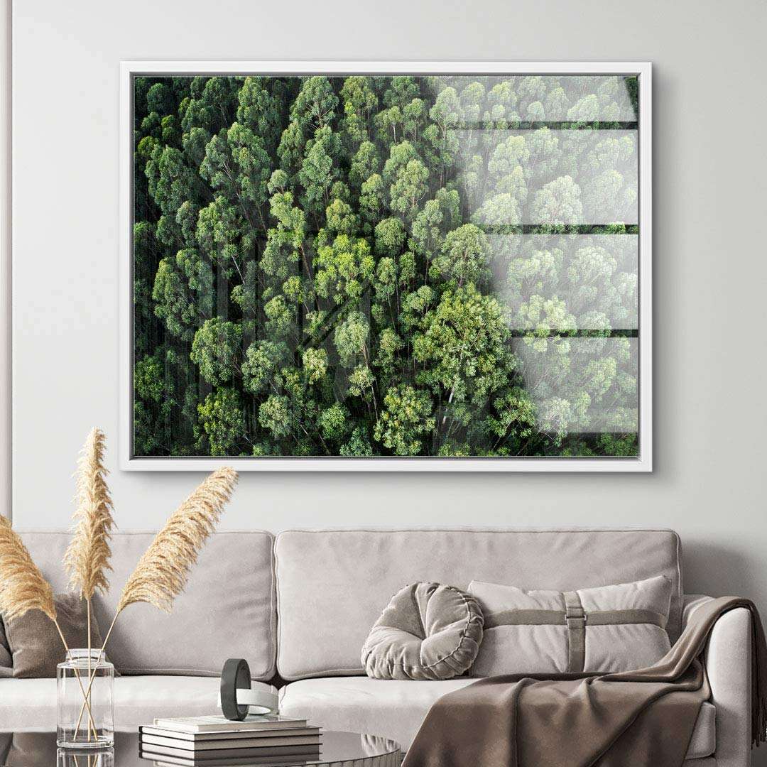 Modernes Wandbild mit Drohnenaufnahme eines grünen Waldes über beigem Sofa im Wohnzimmer