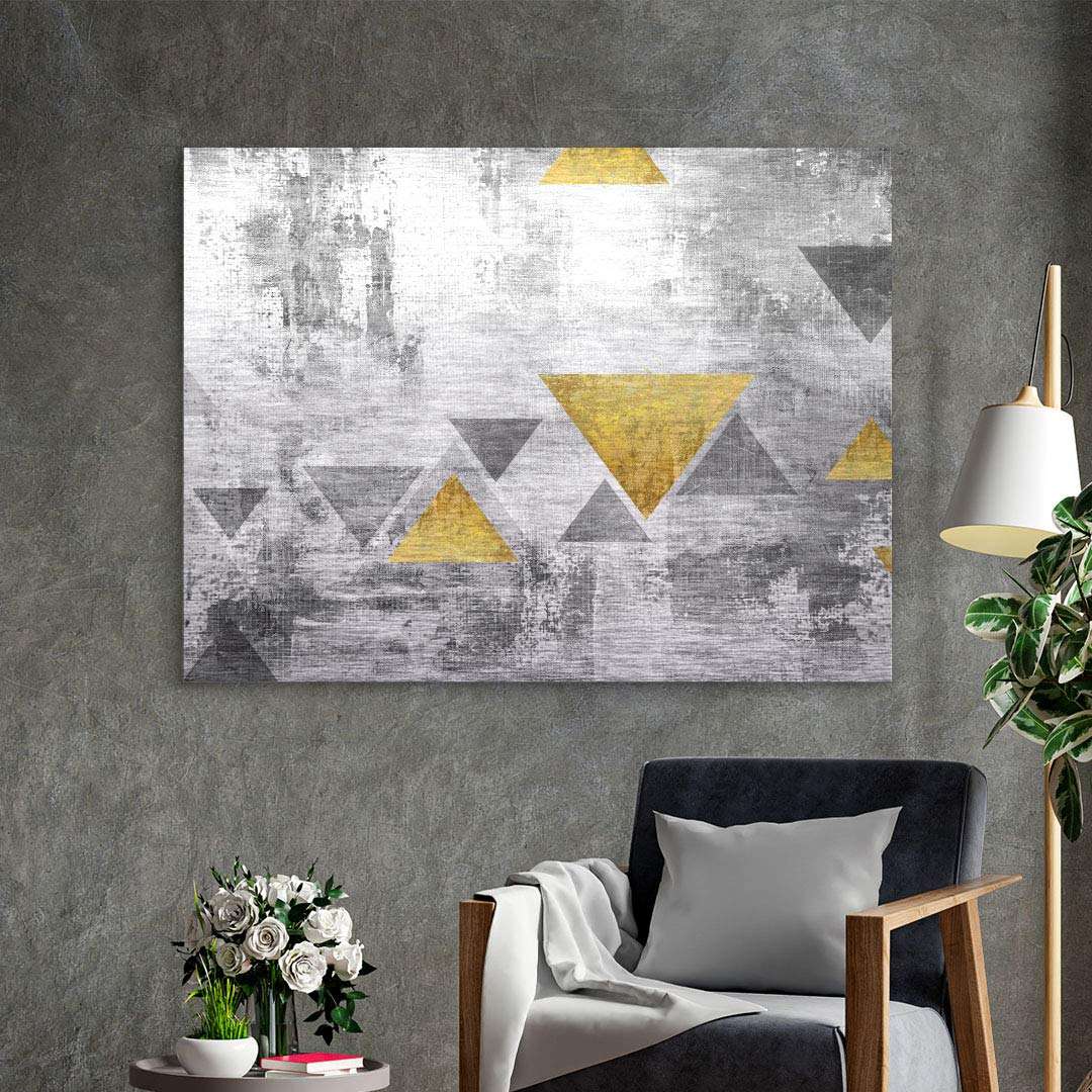 Modernes Wandbild mit goldenen und grauen Dreiecken auf grauer Struktur im Wohnzimmer