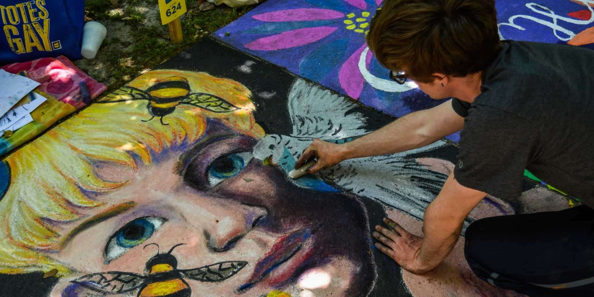 Straßenkünstler malt buntes Kreideportrait eines Kindes mit Bienen und Vogel auf Gehweg