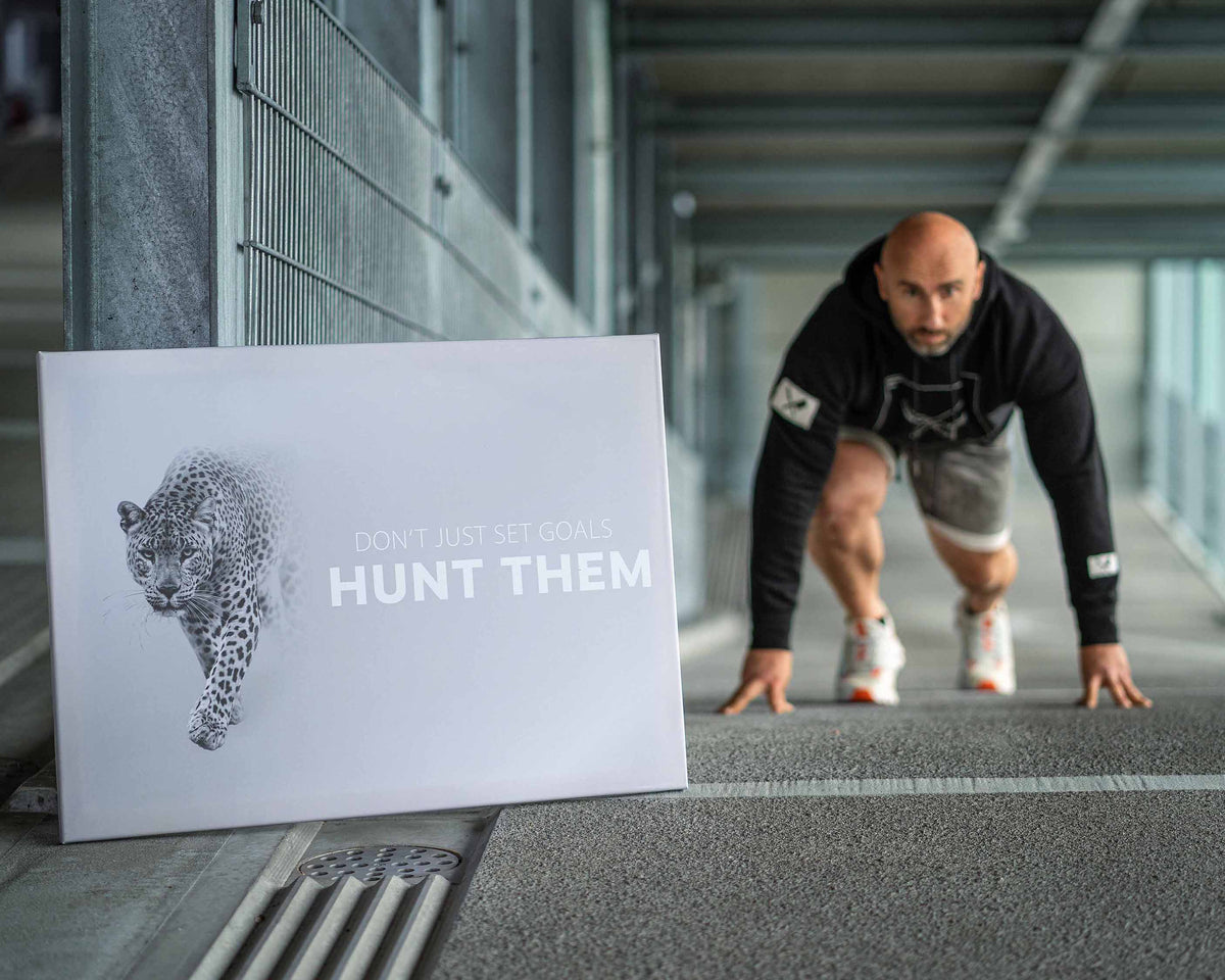 Motivationsbild mit Leopard und Text "Don't just set goals, hunt them", Sportler in Startposition
