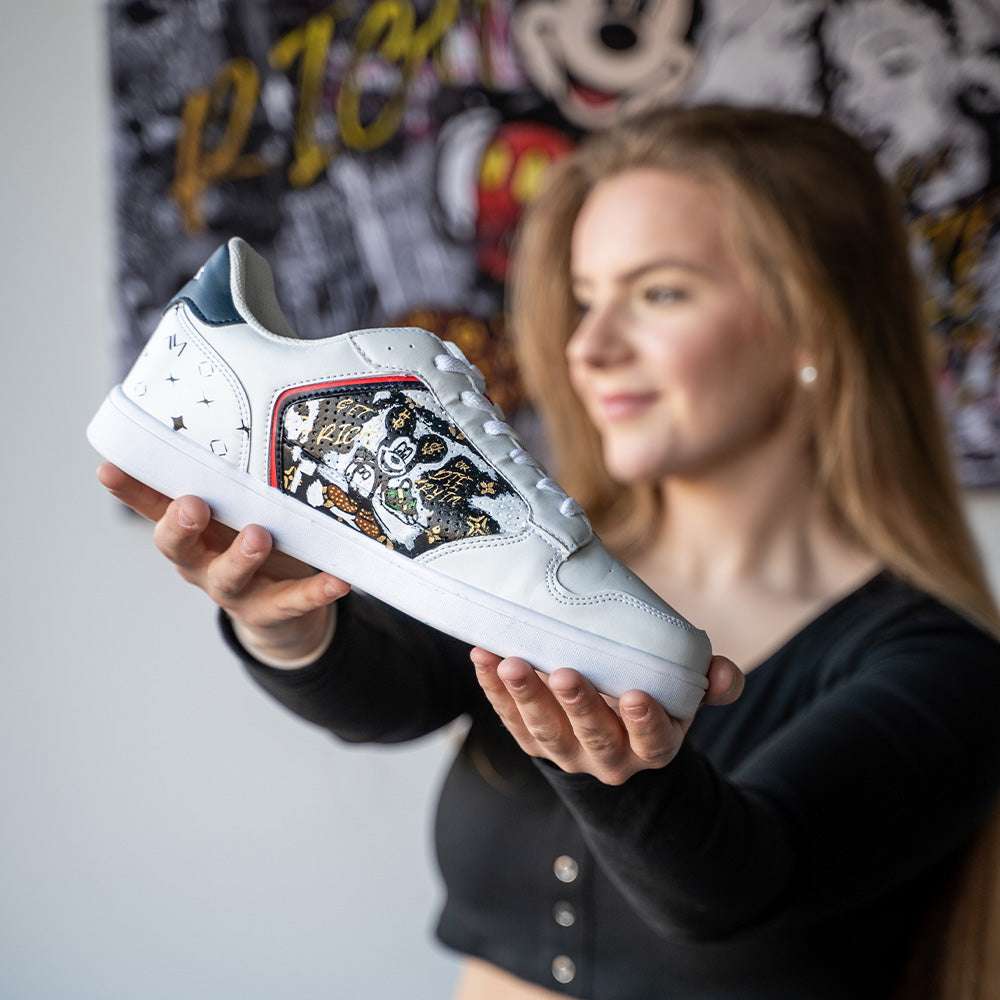 Frau hält individuell gestalteten weißen Sneaker mit bunter Kunst-Graffiti am Seitenpanel