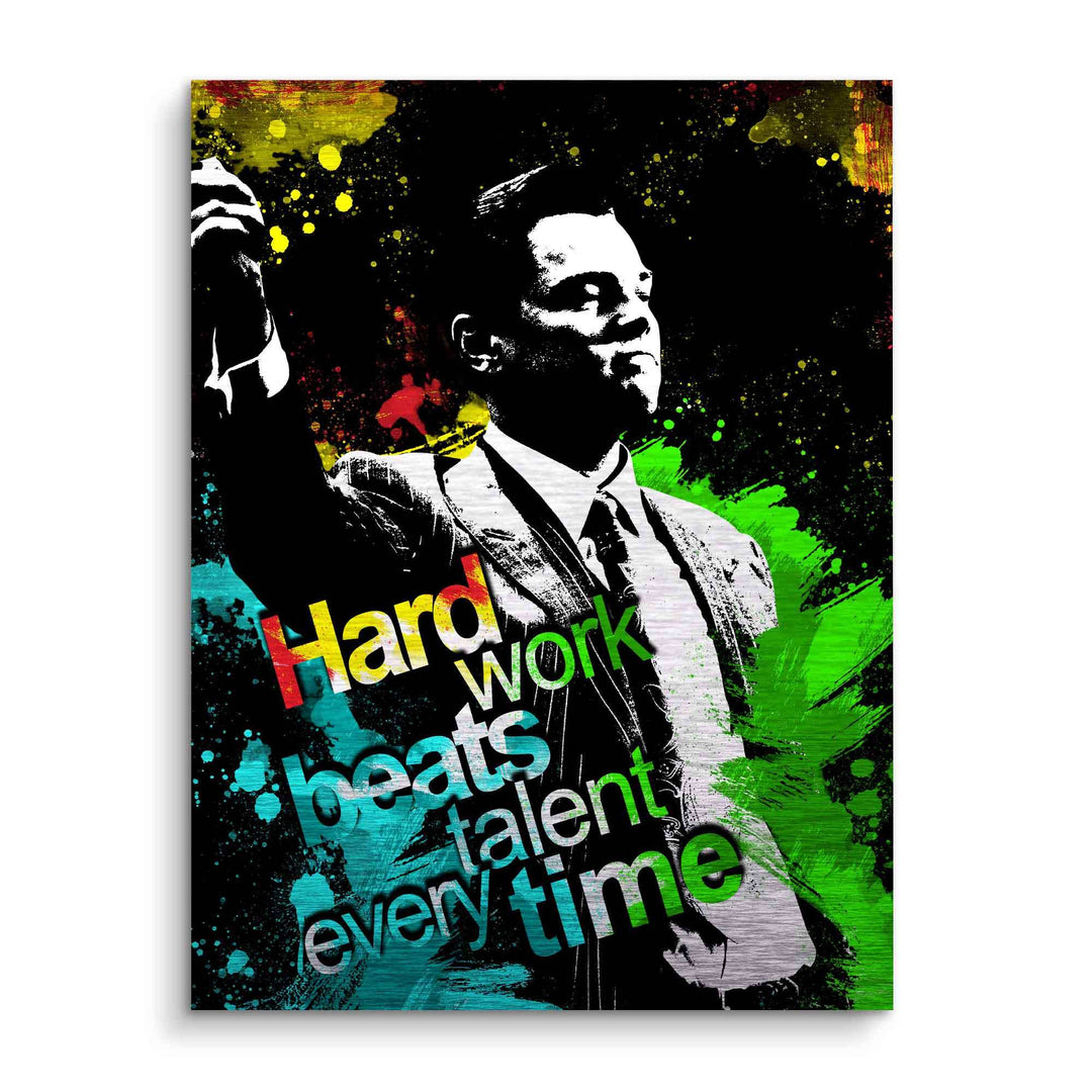 Motivationsbild eines Anzugträgers mit bunten Farbspritzern und dem Text 'Hard work beats talent every time'.