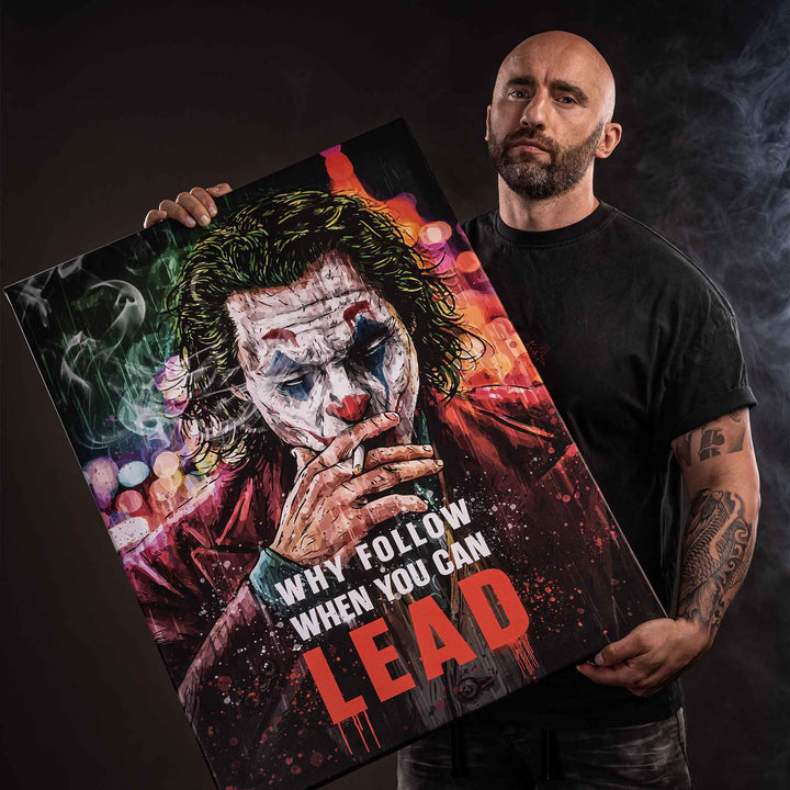 Mann hält Wandbild mit Joker Pop Art Motiv und Motivationsspruch, düsterer Hintergrund