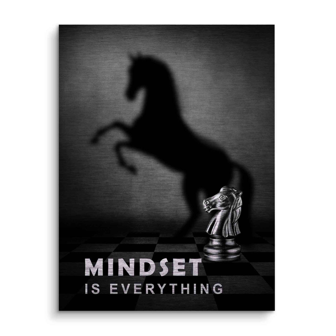 Schachfigur Springer auf Schachbrett, wirft Schatten eines starken Pferdes, Motivationsbild mit Text Mindset is everything.