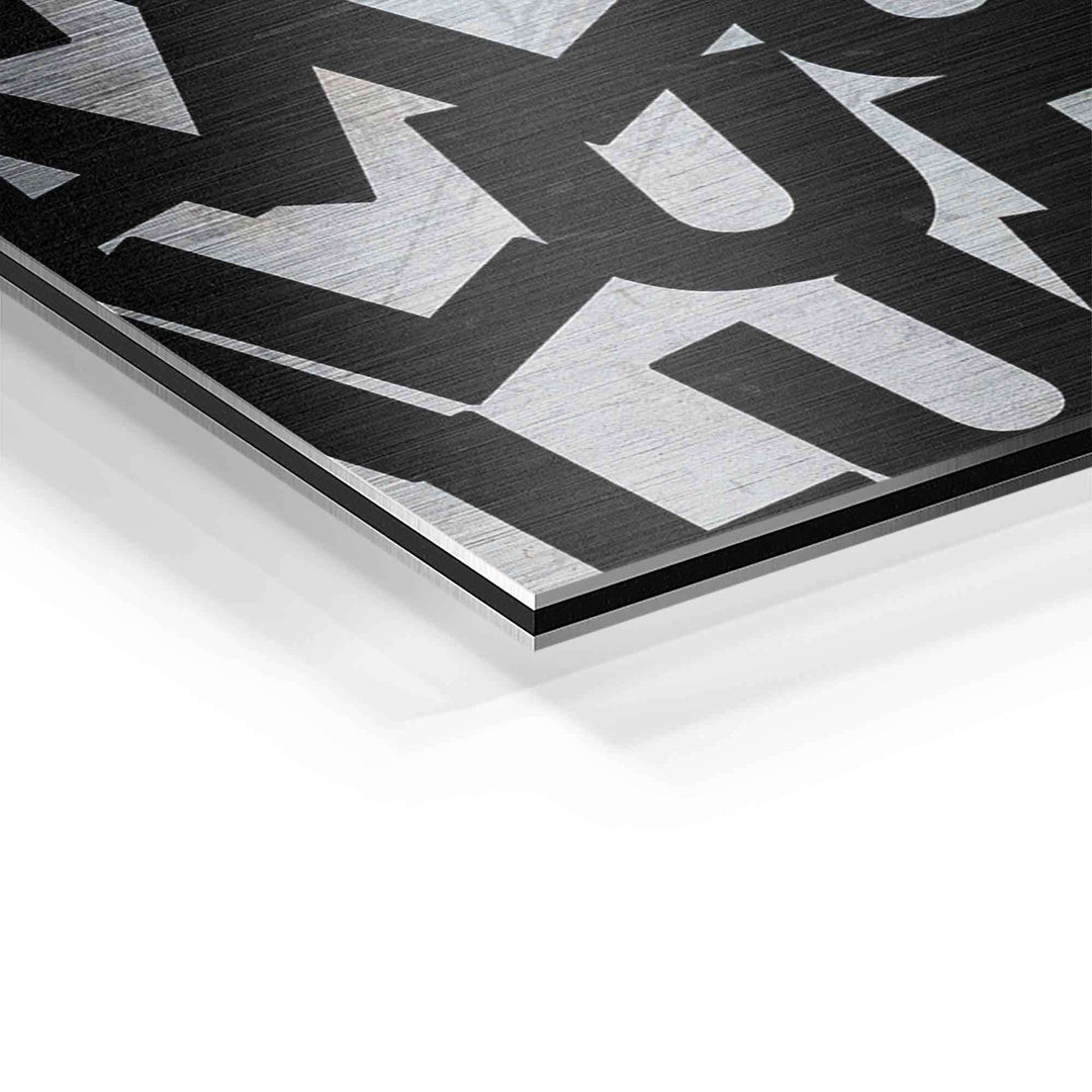 Detail eines Motivationsbildes auf gebürstetem Aluminium mit schwarzem Schriftzug
