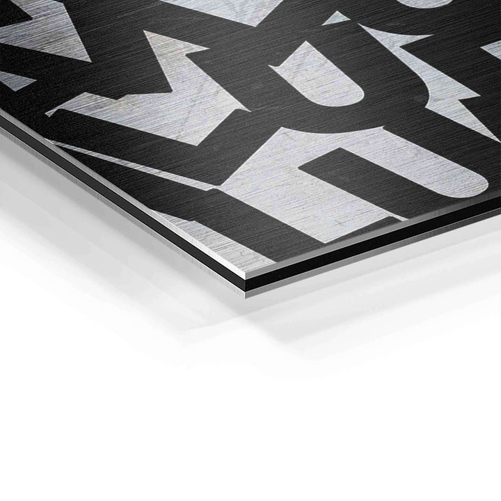 Detail eines Motivationsbildes auf gebürstetem Aluminium mit schwarzem Schriftzug