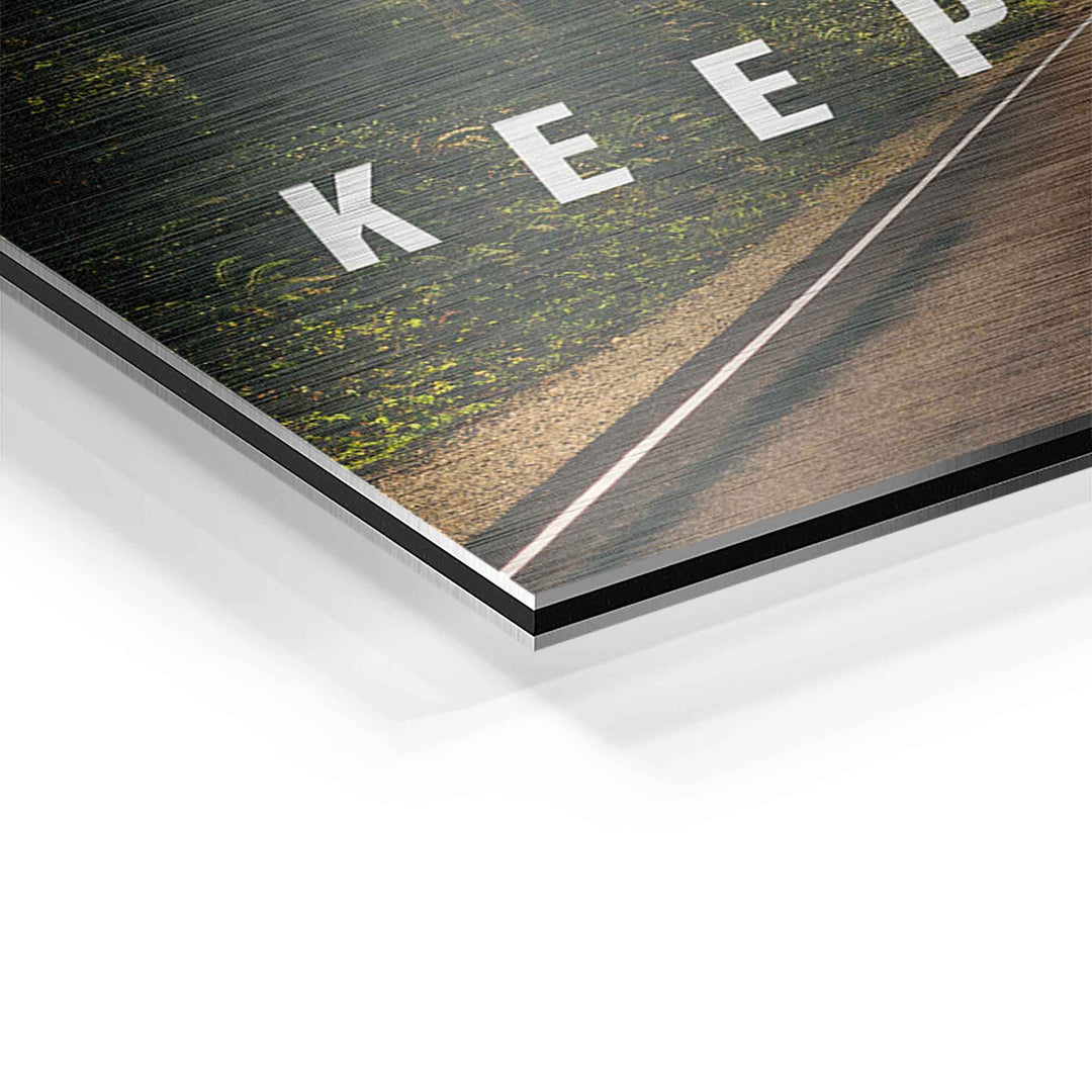 Detailaufnahme Motivationsbild mit Waldstraße und Text auf gebürstetem Aluminium