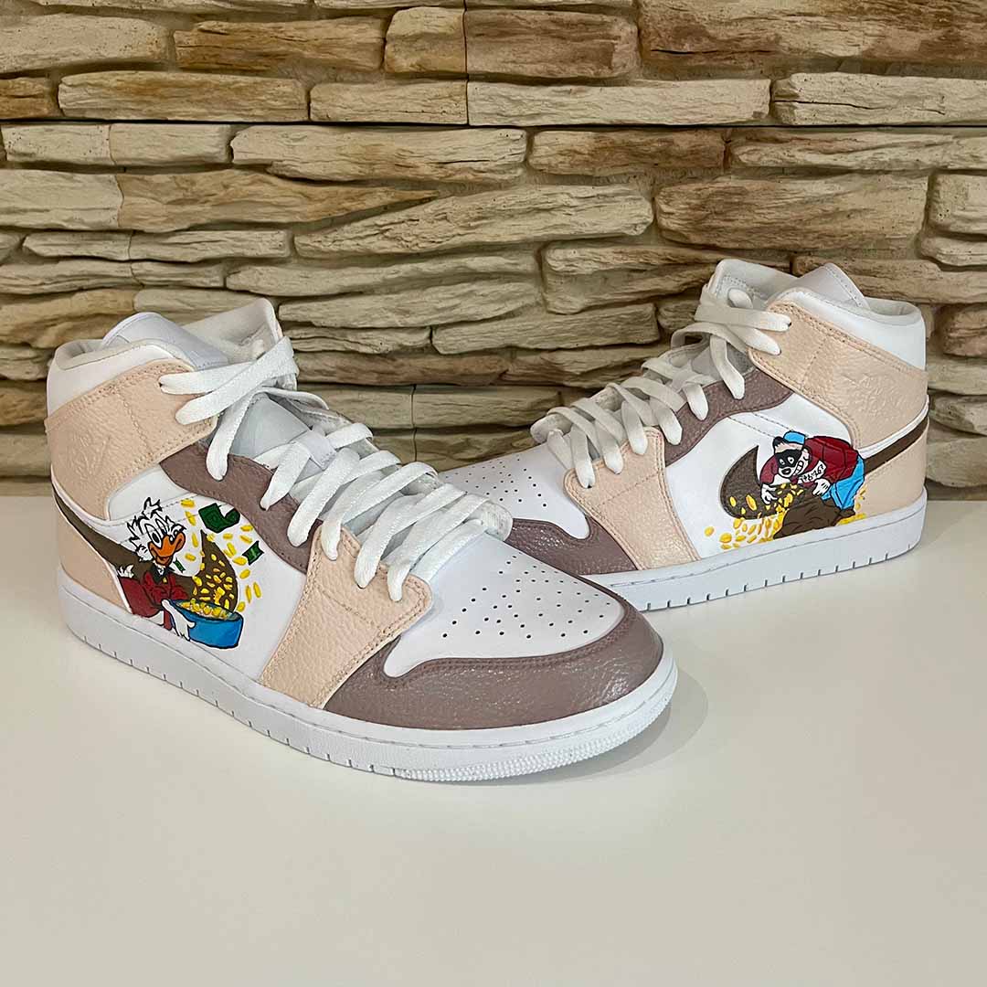 Individuell gestaltete Sneaker mit Comic-Motiven, beige und weiß vor Steinwand
