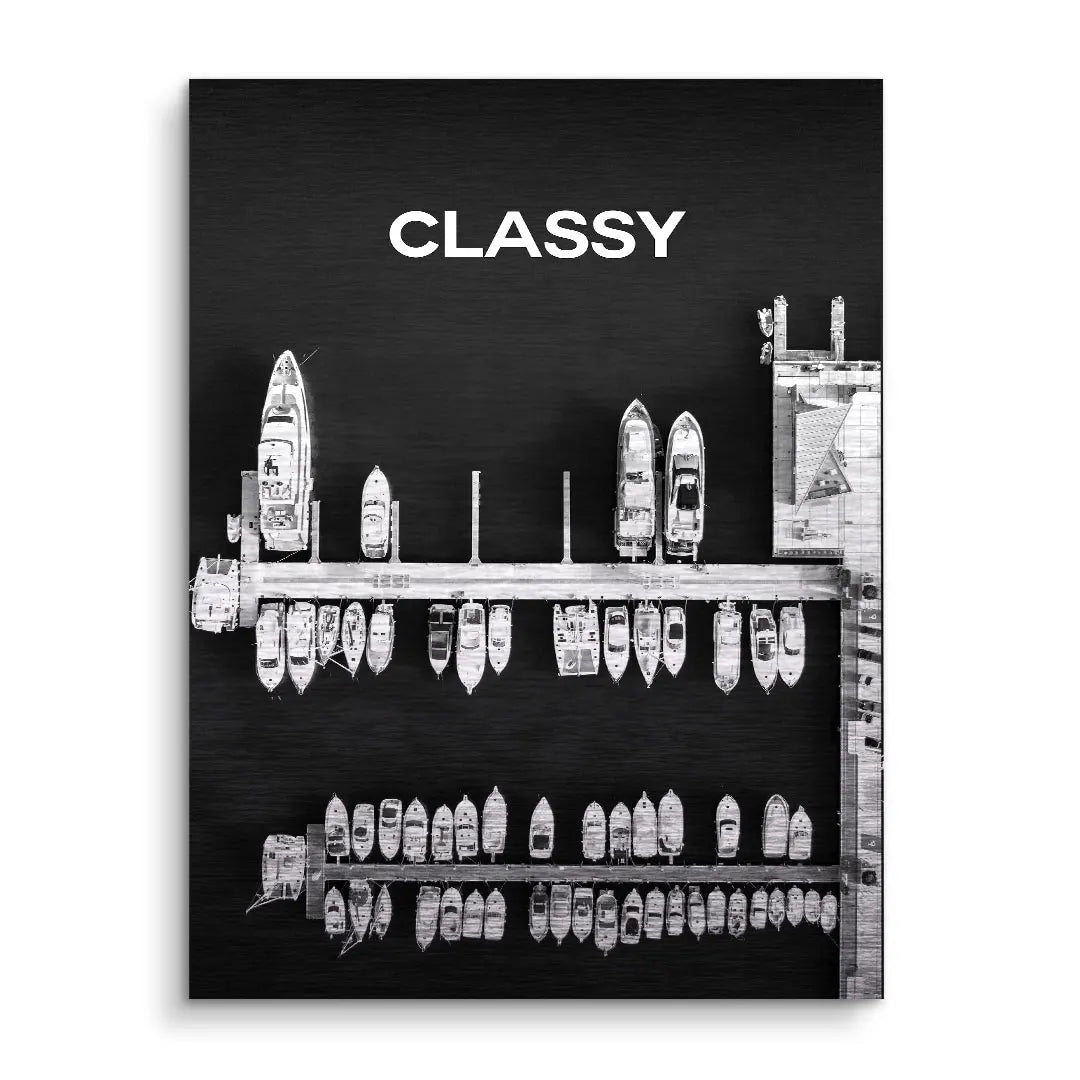 Schwarzes Wandbild mit weißem Schriftzug CLASSY und Luftaufnahme moderner Yachten am Steg