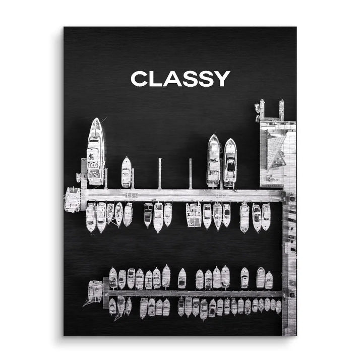 Schwarzes Wandbild mit weißem Schriftzug CLASSY und Luftaufnahme moderner Yachten am Steg