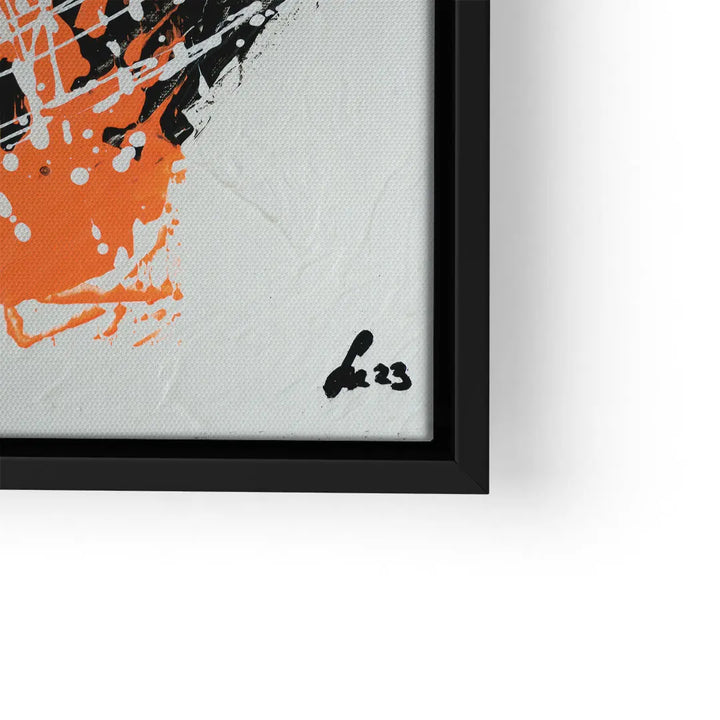 Detail eines modernen Wandbilds mit abstrakter oranger und schwarzer Farbspritzkunst im schwarzen Rahmen