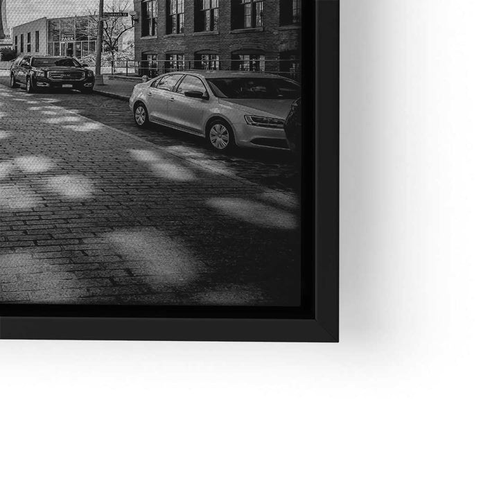Schwarz-weiß Wandbild mit Stadtstraße, parkenden Autos und Ziegelgebäuden in modernem Rahmen