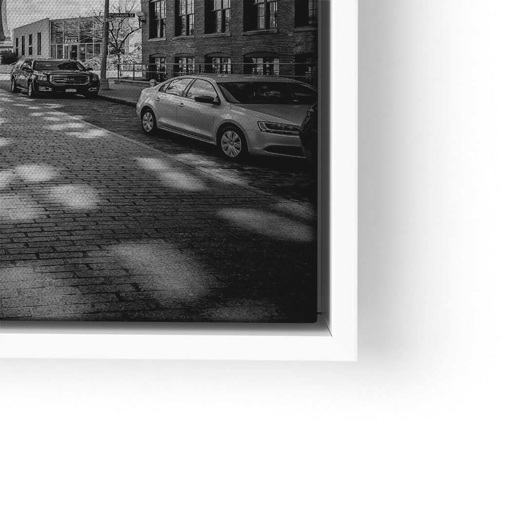 Schwarz-weiß Wandbild mit Autos auf Kopfsteinpflaster, moderne Gebäude im Hintergrund