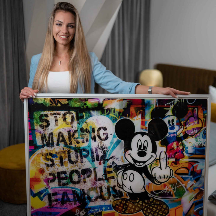 Frau hält Pop Art Wandbild mit bunter Micky Maus und Graffiti-Elementen im modernen Raum