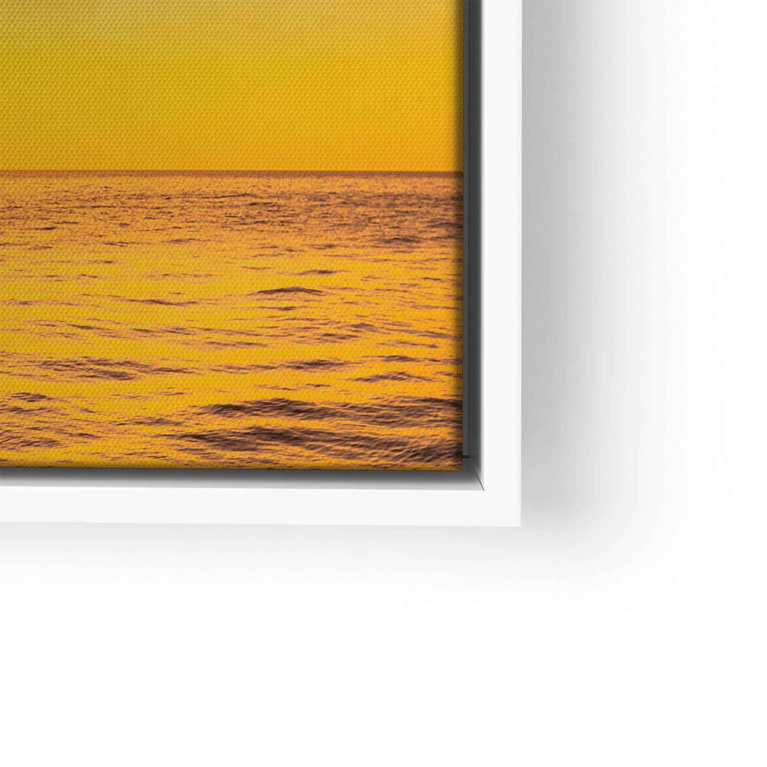 Detail eines Wandbilds mit Sonnenuntergang über Meer in Gelb-Orange, moderner weißer Rahmen